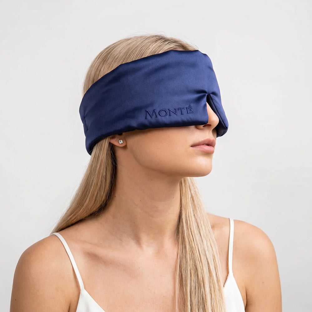Monté midnight blue silk sleep mask on a woman in three-quarter profile – studio shot with embroidered logo closeup